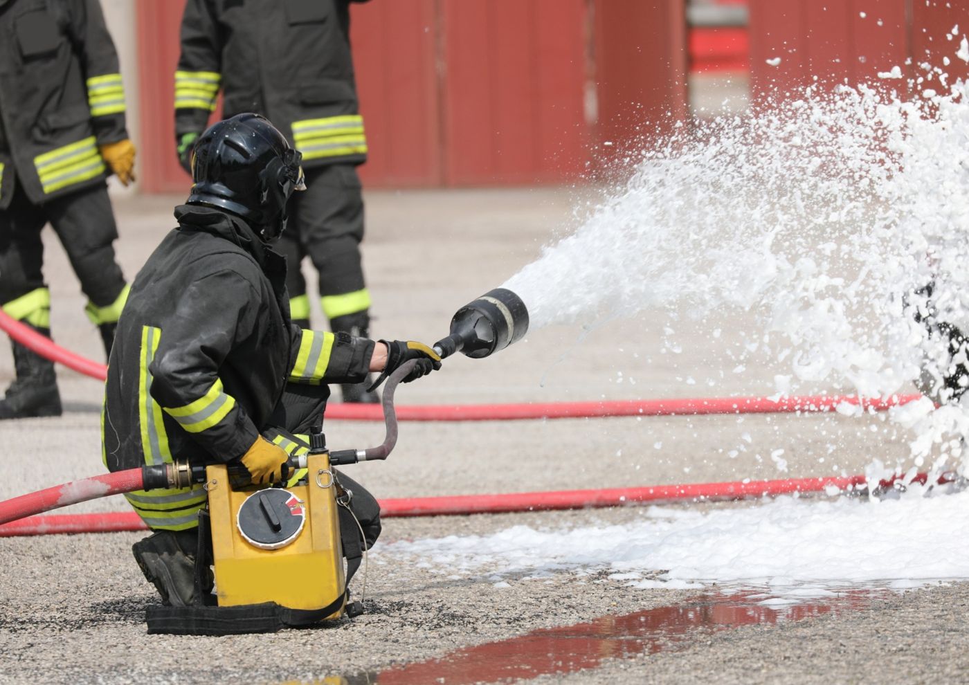 Firefighter discharging foam from a handline during a live exercise
